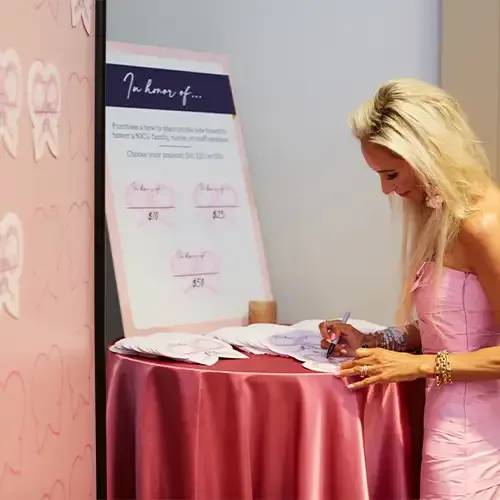 Woman writes on laminated paper bow to attach to wall of bows
